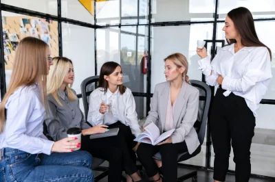 A group of professional women having a discussion in a modern office setting.